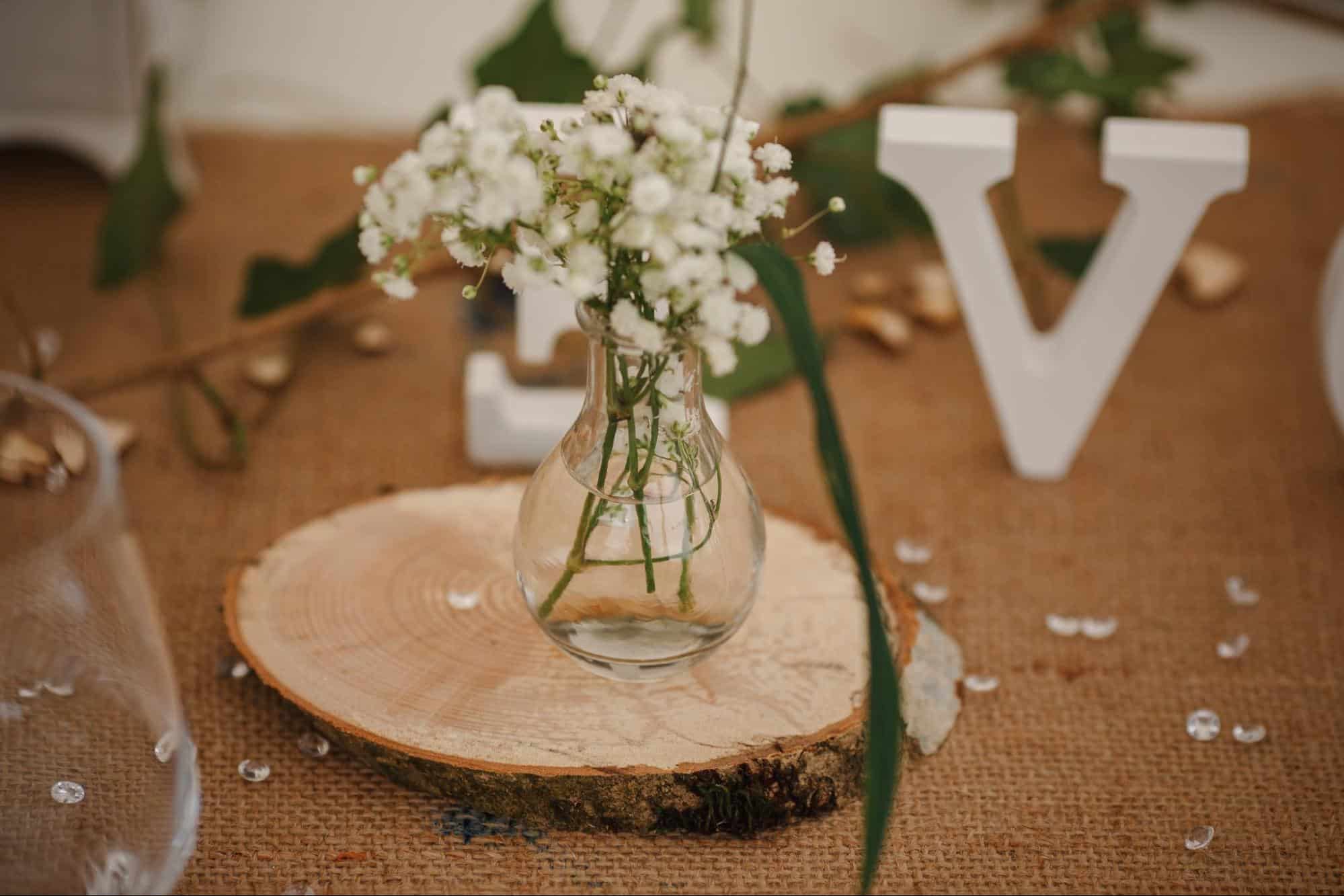 jar of baby's breath sitting on wood round as rustic wedding centerpiece